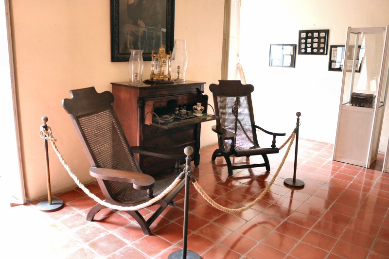 The reading corner with the wooden dropdown desk cabinet and two wooden chairs