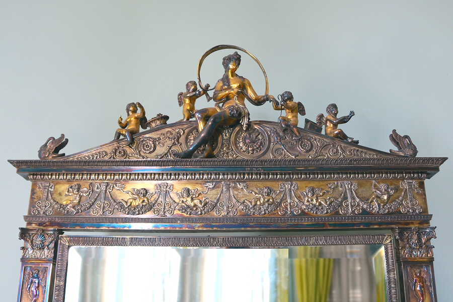  The mirror, framed by silver plate, is topped by a seated nude female figure, representing Venus, and two putti on each side of it. It is the design of Pierre-Philippe Thomire.