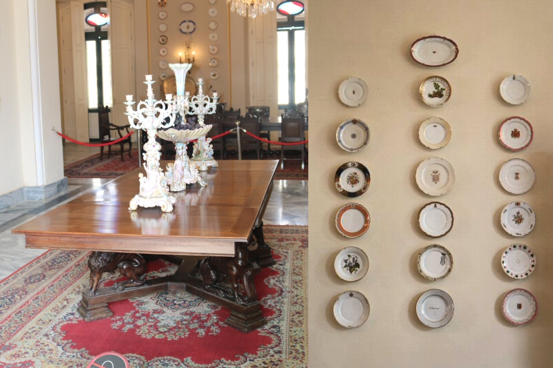 Several dinner tables with different motives, but in majority the same size, are enriching the walls of the Antesala Comedor. A wooden table is placed in the middle of the room with ceramic candelabrums on it.